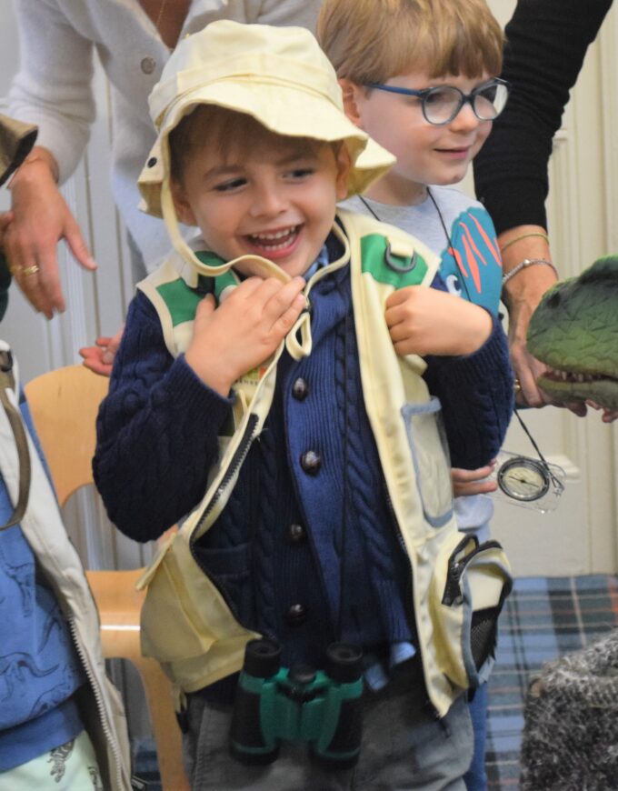 children looking at a pretend dinosaur