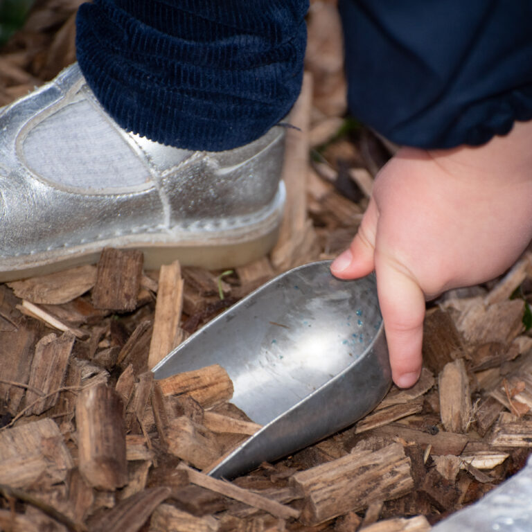 child scooping wood chips