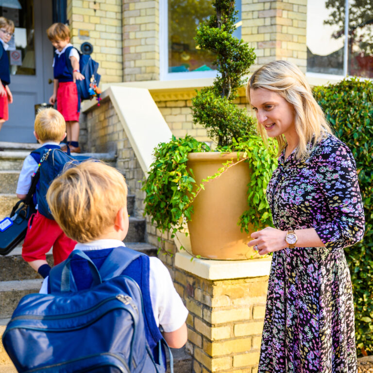 teacher greeting children into the school